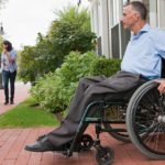 Middle aged caucasian male in wheelchair exiting door